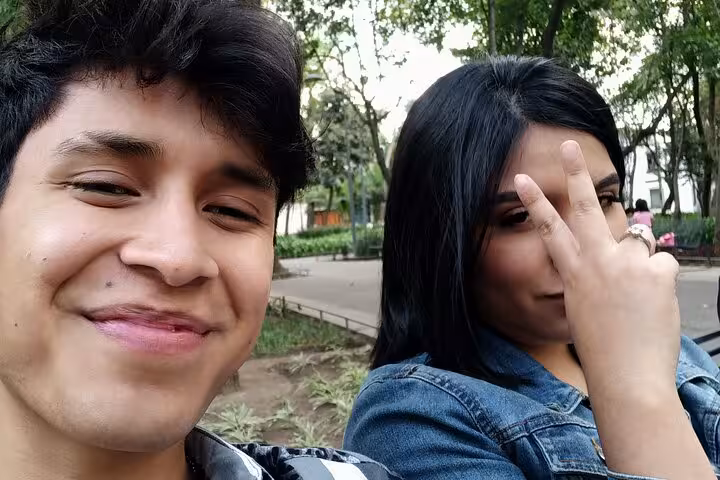 Two young people taking a selfie in Chimalistac park, Mexico City, surrounded by trees