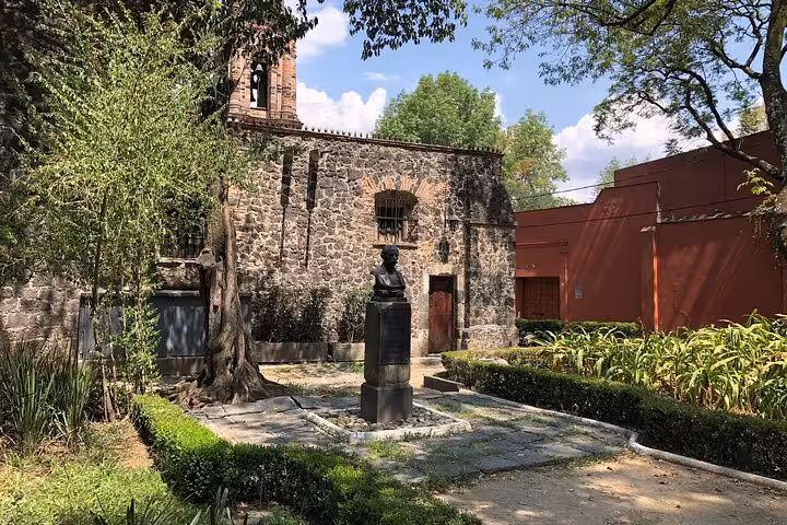 Historic stone chapel with bronze bust sculpture in garden courtyard, Chimalistac neighborhood, Mexico City