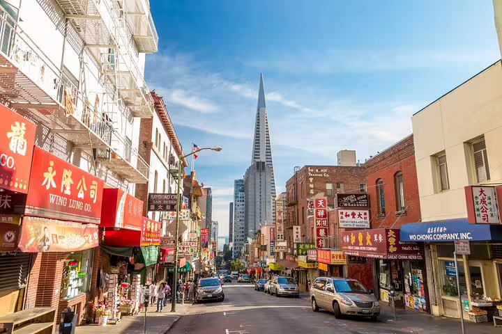 Colorful Chinatown San Francisco street with Chinese signs, shops, and Transamerica Pyramid in background