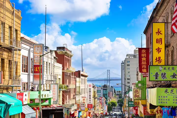Colorful Chinatown San Francisco street with Chinese signs, historic buildings, and Bay Bridge in background