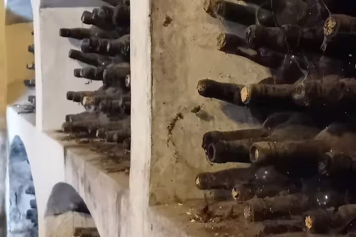 Close-up of dusty wine bottles aging in a rustic Chinchón winery, highlighting the heritage of Madrid's wine experience.
