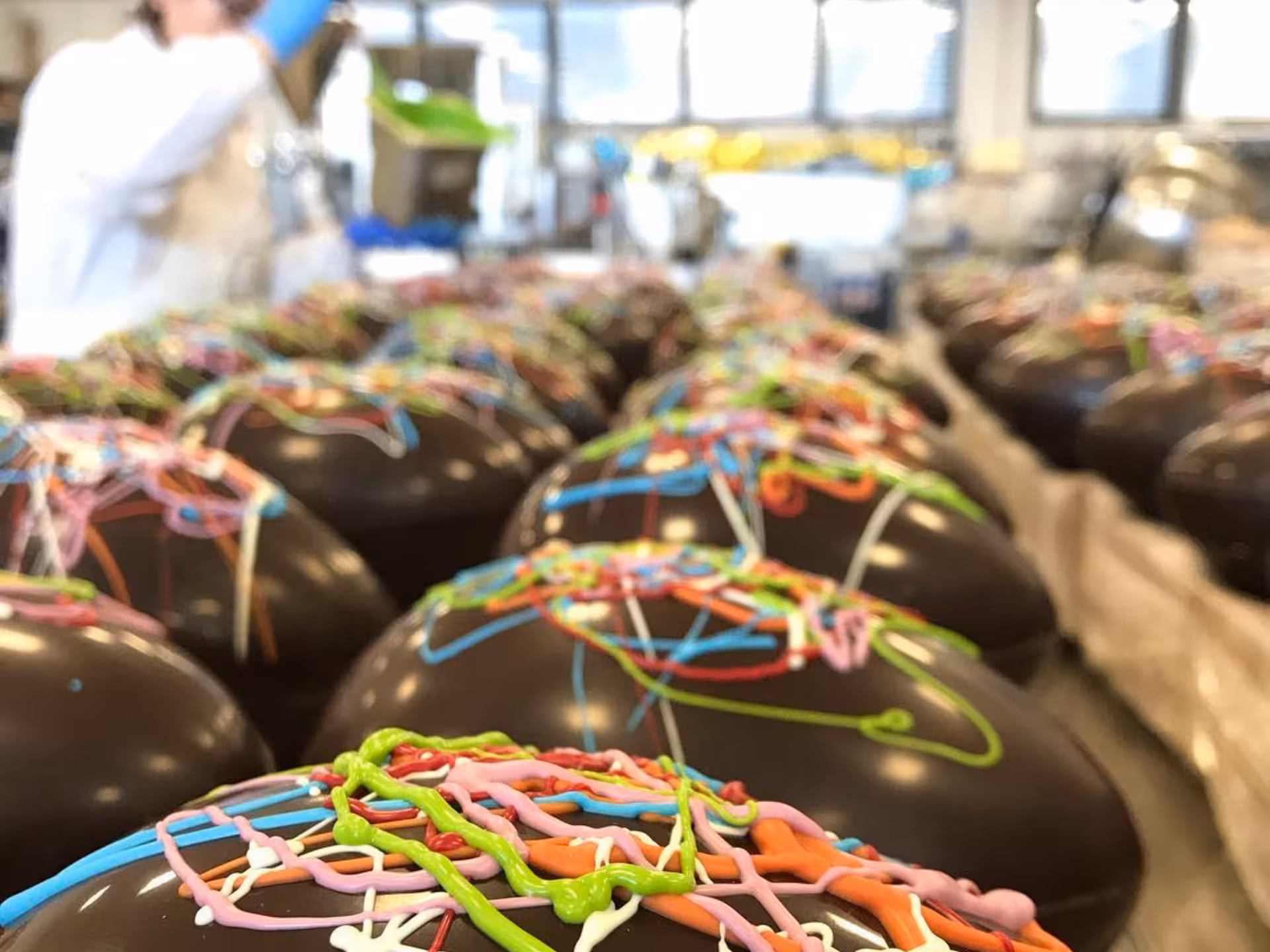 Rows of chocolate eggs with colorful icing being prepared in a factory near Alessandria.