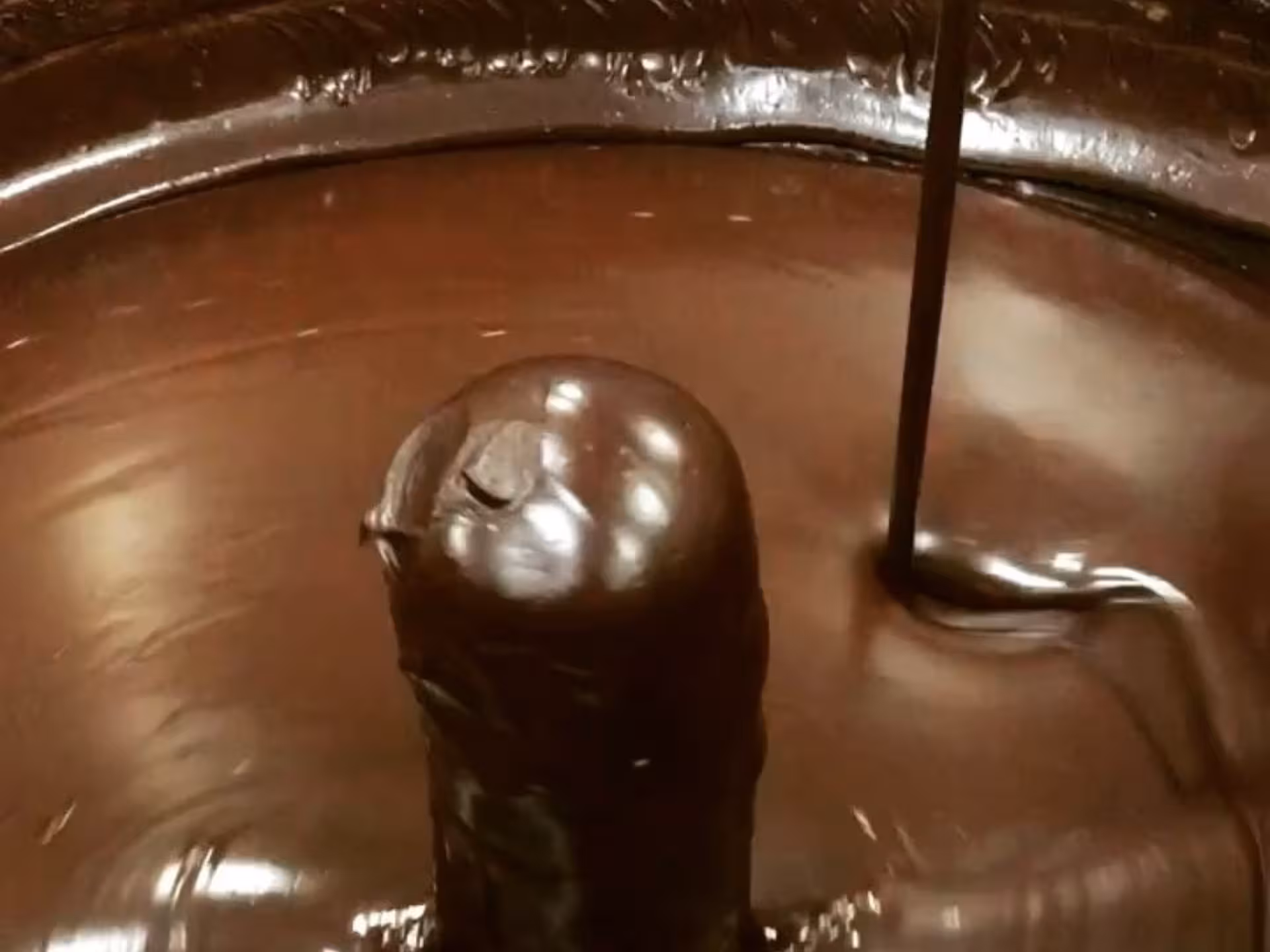 Rich chocolate flowing in a mixing machine at a factory near Alessandria, perfect for a sweet tour and tasting.