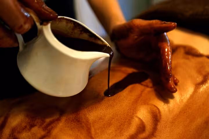 Warm chocolate oil poured during Sharm El Sheikh Chocolate Magic Bath Spa Experience body massage