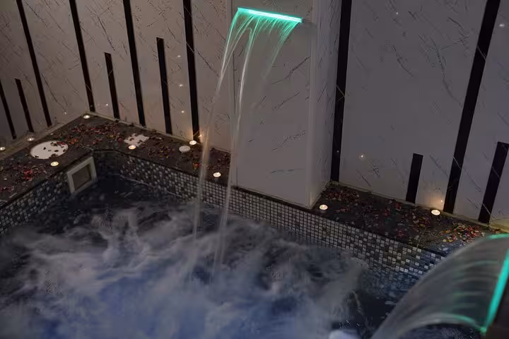 Waterfall shower jet into bubbling hot tub with candlelit petals at Chocolate Magic Bath Spa Experience, Sharm El Sheikh