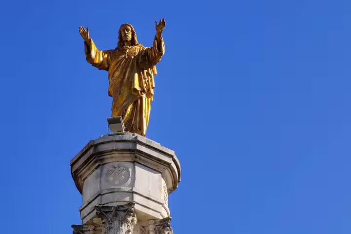 Golden statue of Christ atop a monument against a clear blue sky in Fatima, highlighting cultural landmarks on a private day tour.