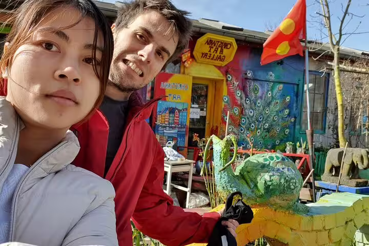 Couple taking selfie in front of colorful Christiania art gallery with peacock mural in Copenhagen