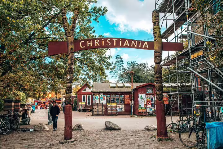 Entrance gate to Christiania with carved wooden totem poles and sign in Copenhagen