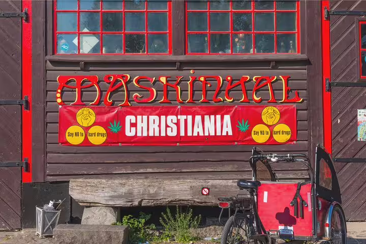 Colorful "Christiania" sign in Vesterbro, Copenhagen, with bike, highlighting unique sights on private tour of vibrant districts.