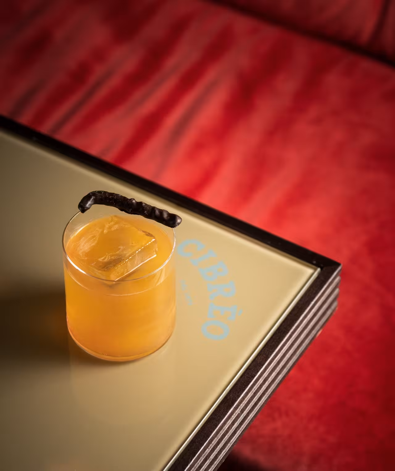 Signature Cibrèo cocktail with large ice cube on mirrored tray in Florence, part of the Cibrèo culinary experience