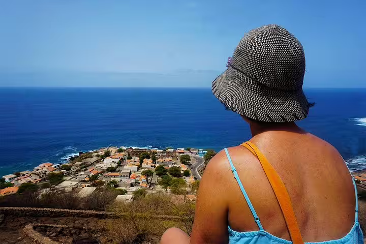 Tourist admiring panoramic views of Cidade Velha and the Atlantic Ocean from a scenic overlook.