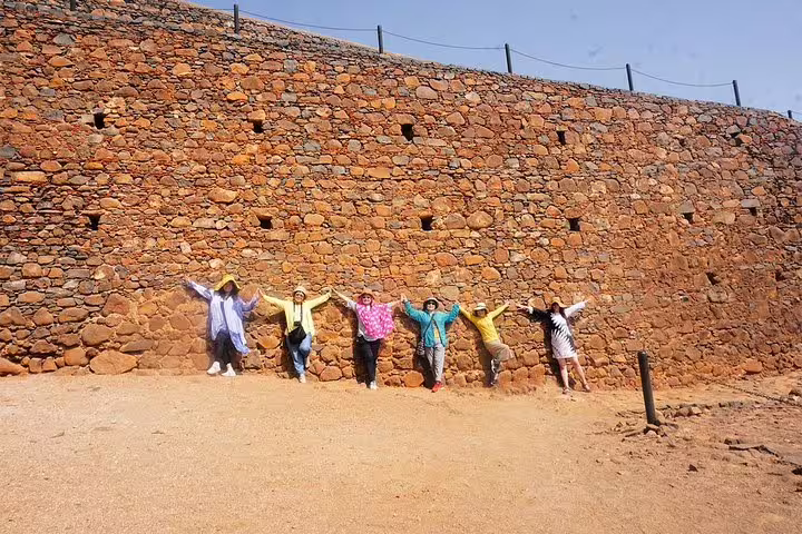 Group posing by fortress stone wall in Cidade Velha on 3-hour guided historic tour from Praia shore excursion