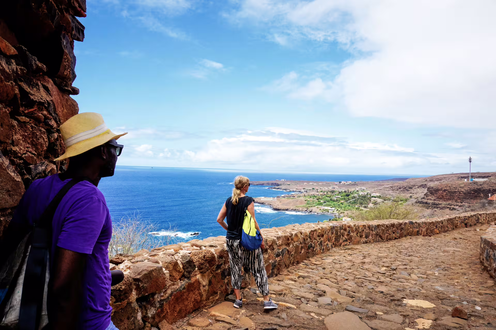 Tourists admire the stunning ocean view from a historic stone path in Cidade Velha, Cape Verde.