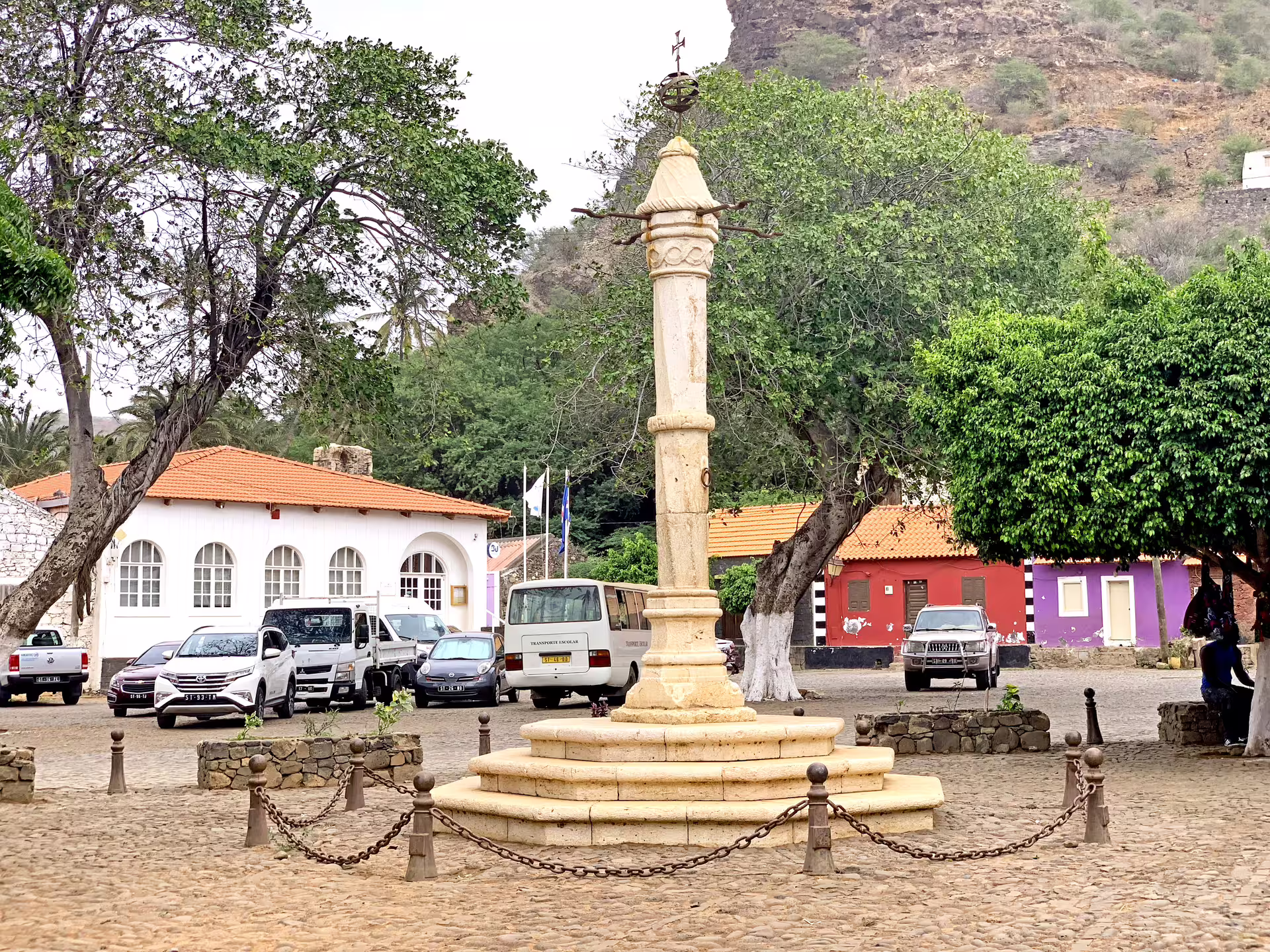 Historic pelourinho in Cidade Velha's square surrounded by colorful buildings and lush greenery.