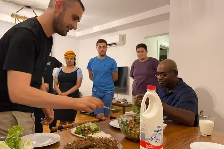 Host serves homemade çiğ köfte and salad at home, sharing Turkish dinner with traditional music night tour