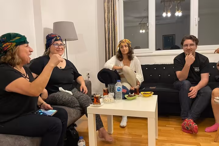 Guests relax in a Turkish home after çiğ köfte cooking class, enjoying tea and conversation during music night