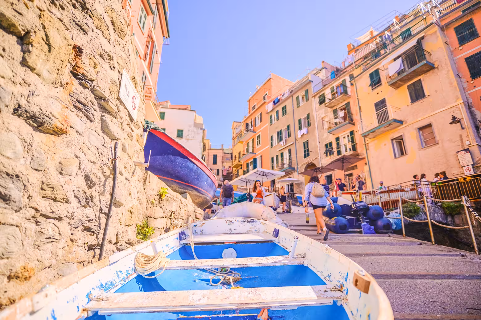 Close-up of a traditional blue boat on the stone walkway of Riomaggiore, Cinque Terre, surrounded by pastel buildings.