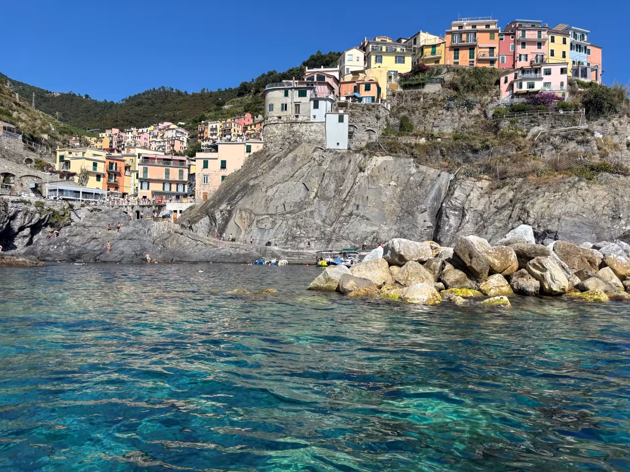 Cinque Terre cliffside village view from a La Spezia full-day boat tour, turquoise sea and rocky coastline