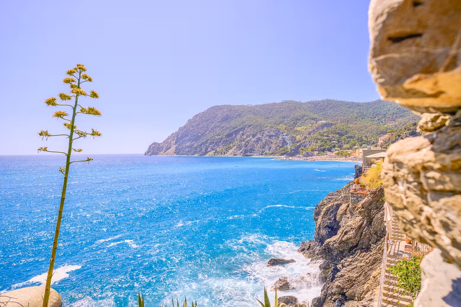 Stunning coastal view of Cinque Terre with turquoise waters and rocky cliffs under a clear blue sky.