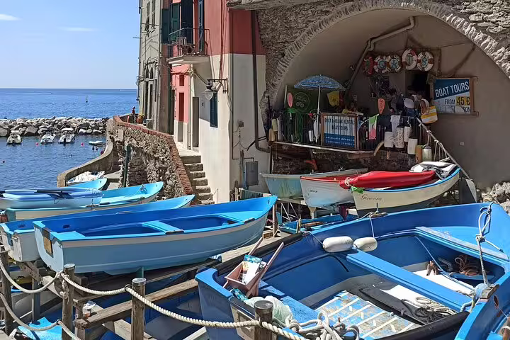 Small colorful boats moored by stone houses in a Cinque Terre village, start point for La Spezia shore excursion