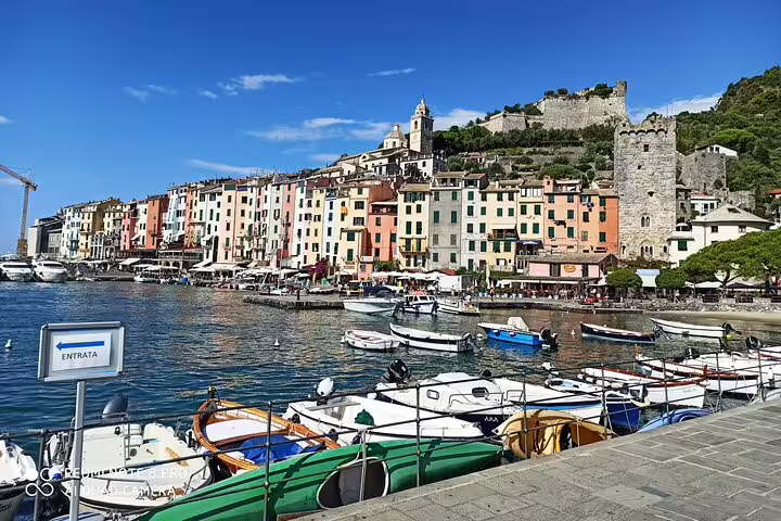 Boats lined up in a vibrant Cinque Terre marina with historic hilltop fort and village, reached via La Spezia transfer