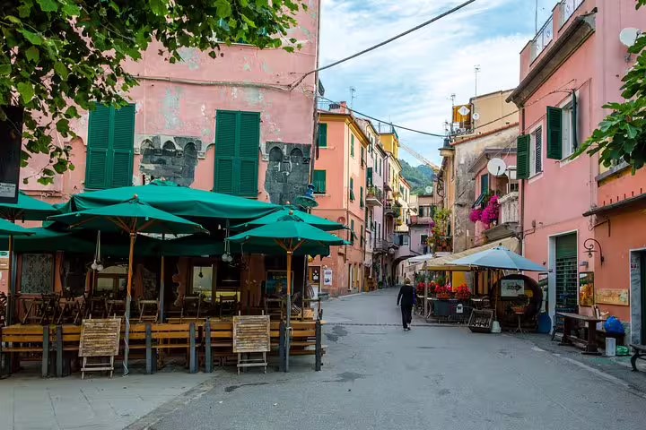 Quiet pastel street with outdoor cafés and green awnings in a charming Cinque Terre village on a private walking tour