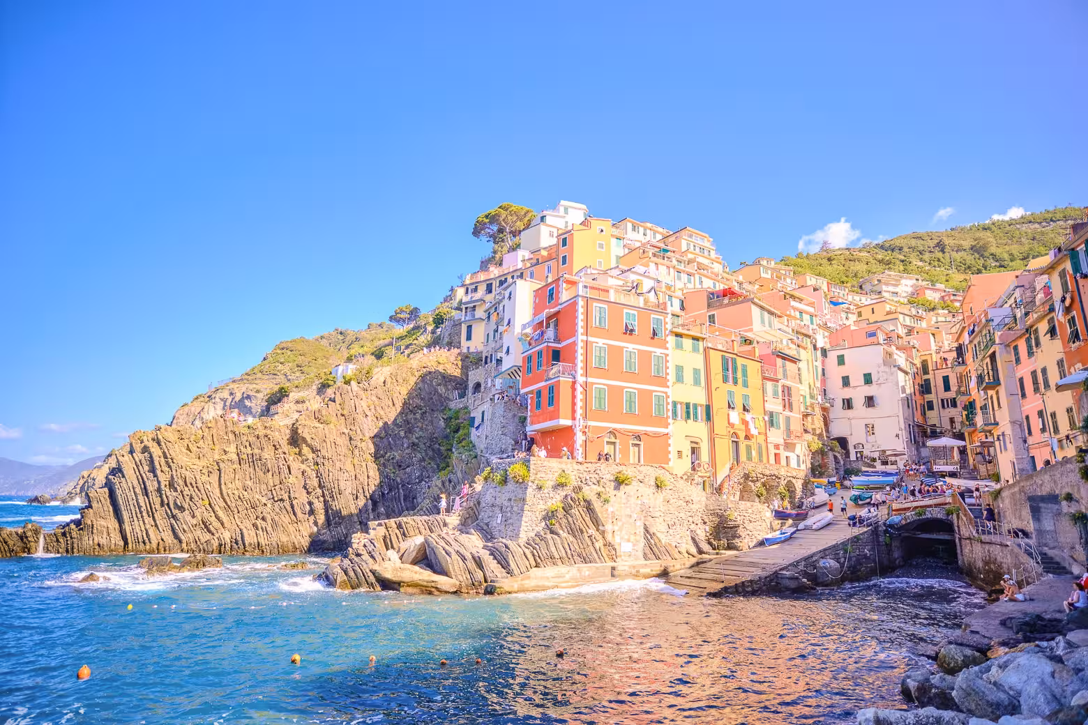 Colorful cliffside buildings of Riomaggiore in Cinque Terre with turquoise sea, perfect for small group tours.