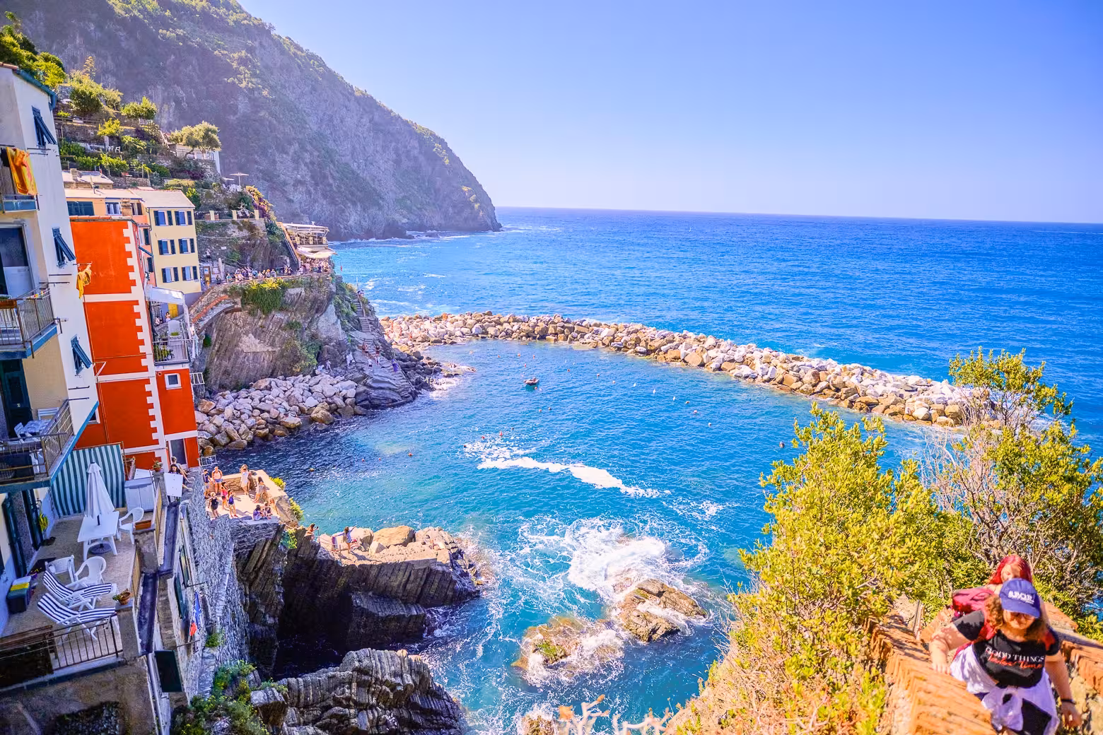 Scenic coastal view of Riomaggiore's rocky shoreline and sparkling blue sea, ideal for Cinque Terre excursions.