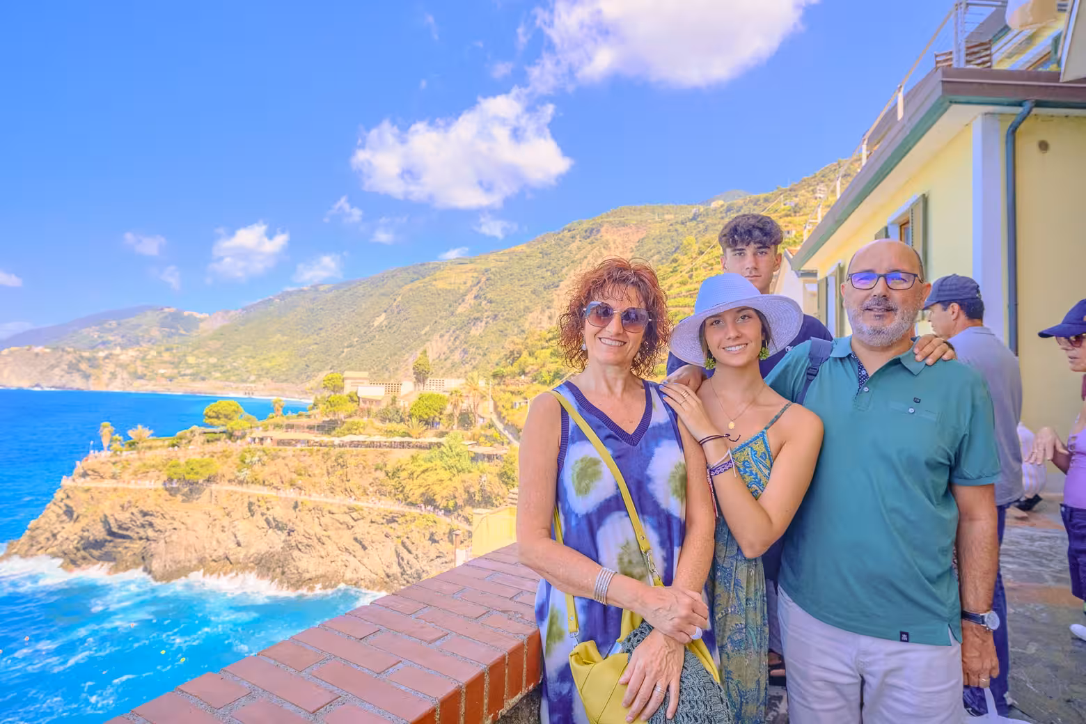 Smiling tourists enjoying a sunny day with stunning coastal views in Cinque Terre National Park.