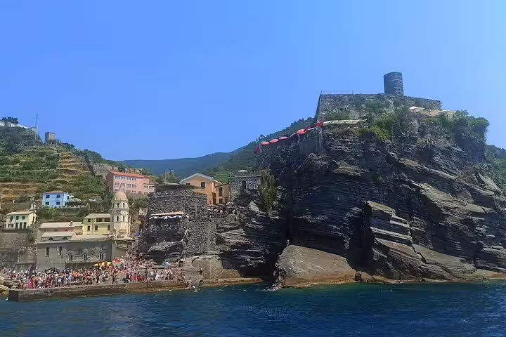 Dramatic cliffs and medieval tower above Vernazza harbor viewed from boat on La Spezia to Cinque Terre cruise transfer
