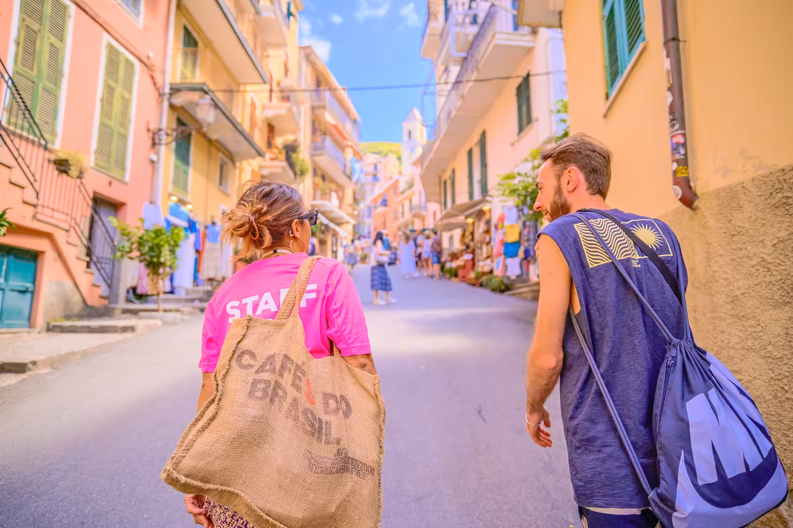 Visitors strolling through vibrant streets of a Cinque Terre village, surrounded by colorful buildings and shops.