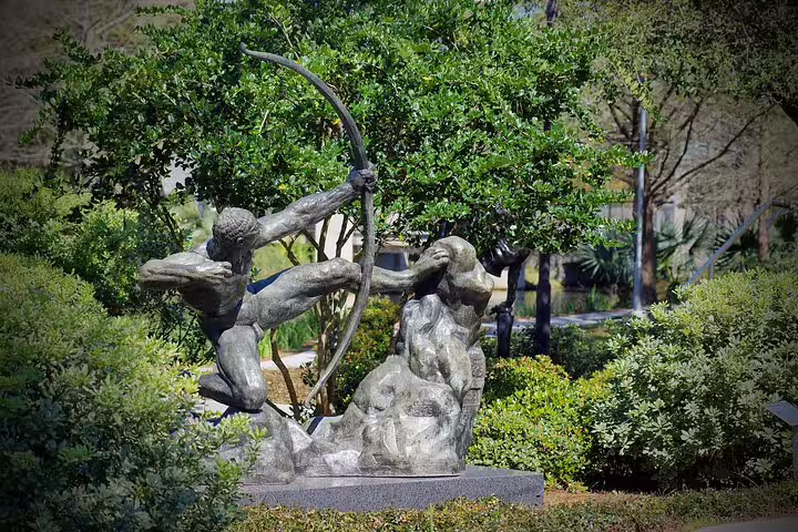 Bronze archer statue drawing bow in lush garden setting at New Orleans City Park