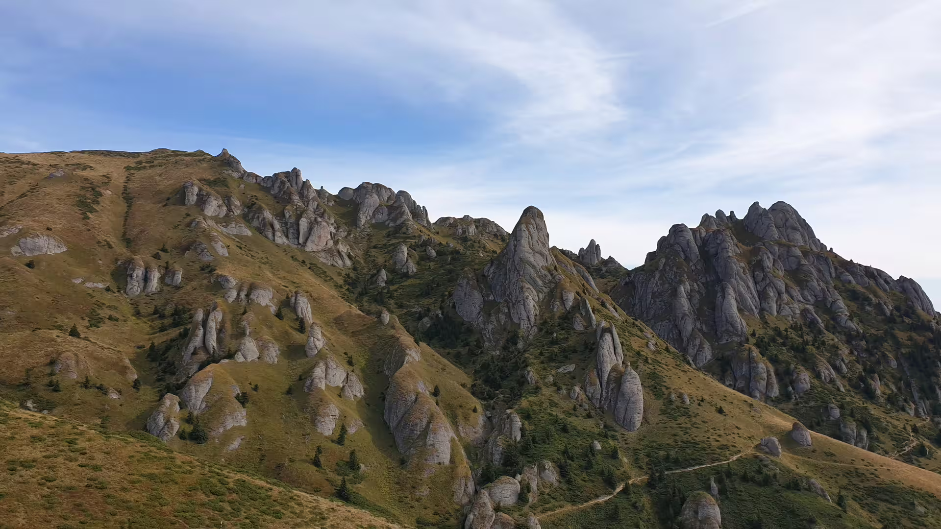 Rocky peaks and stone formations of Ciucas Mountains, Romania, under a blue sky with scattered clouds