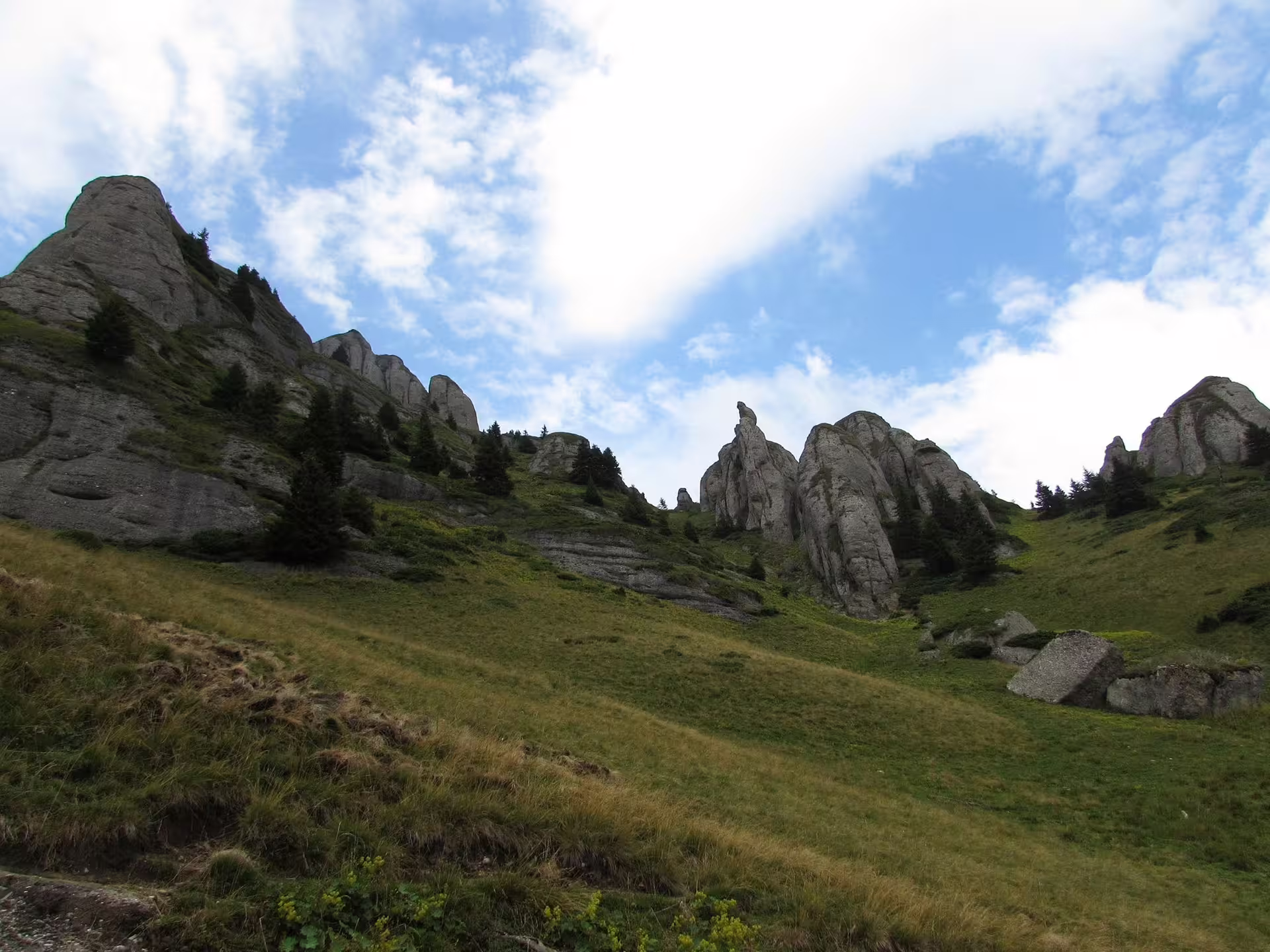 Rocky spires and green alpine meadows on Ciucas Peak hiking trail in Romania
