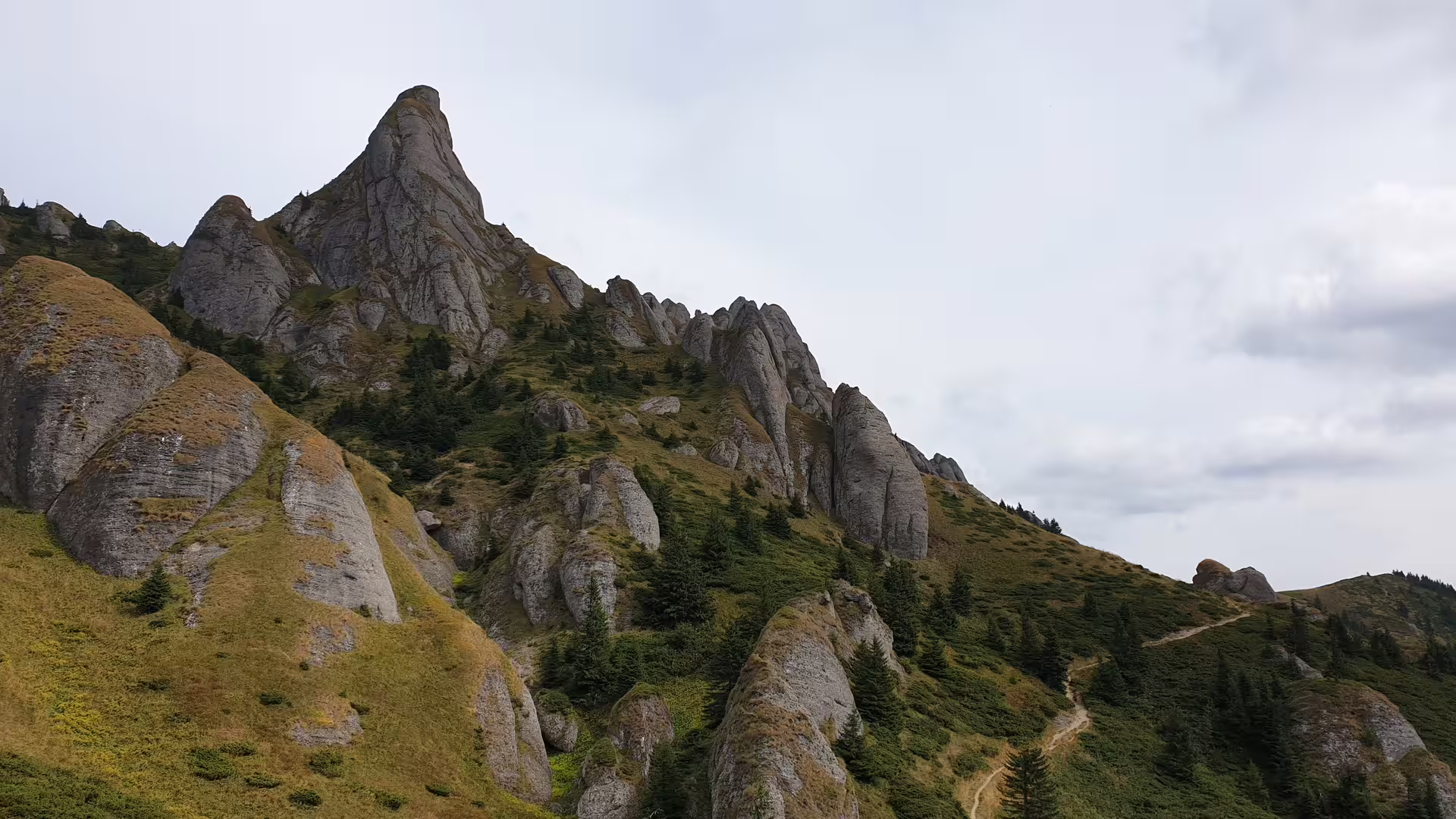 Jagged rocky peaks and spires of Ciucas Mountain with alpine meadows and hiking trail, Romania