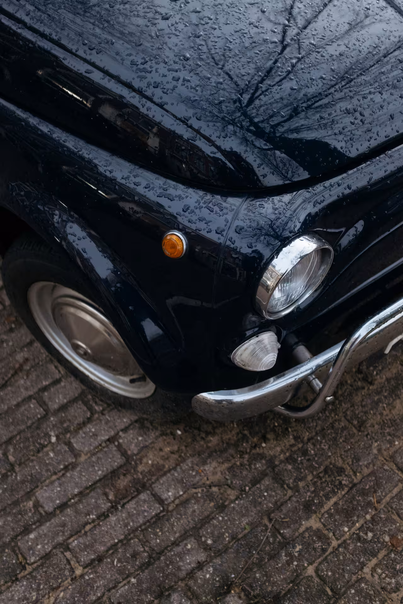 Close-up of classic black Fiat 500 with raindrops, ideal for authentic Tivoli Vintage Tour.