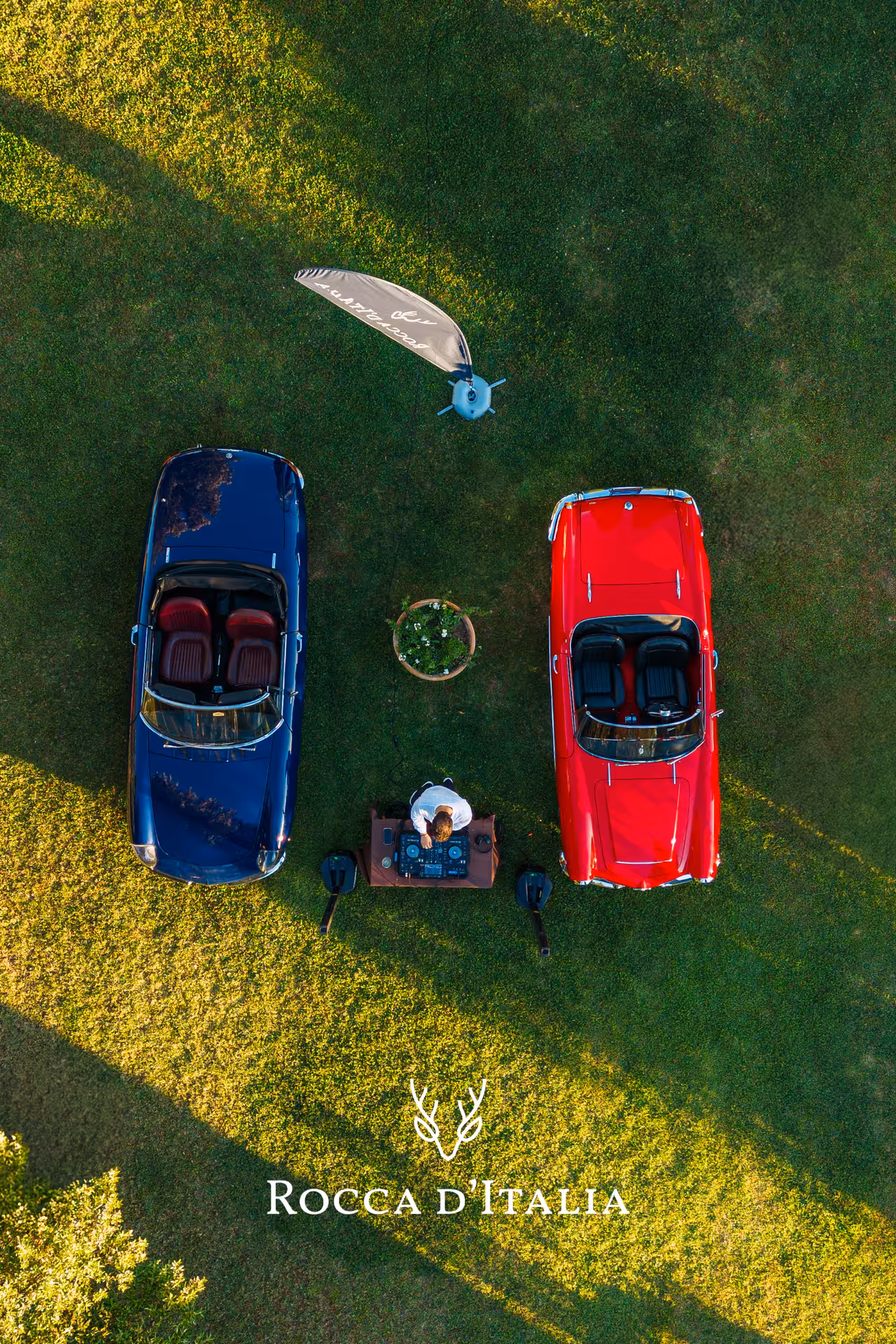 Aerial view of blue and red classic convertible cars parked on green lawn in Chianti, Italy