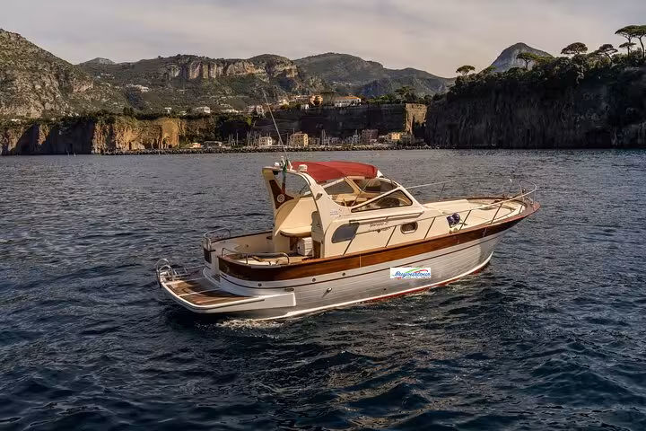 Classic Gozzo boat cruising near Sorrento's scenic cliffs on a private Capri and Positano tour.