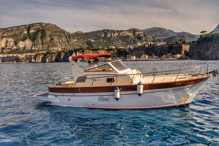 Classic Gozzo 8.50 boat cruising along the scenic coastline from Sorrento to Capri, perfect for a private tour adventure.