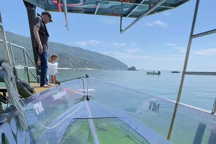 Visitors prepare to embark on a clear boat experience in Sesimbra, with panoramic views of the coastline and clear waters.