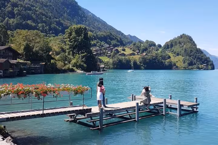 Scenic view of a picturesque lake with tourists on a dock, surrounded by lush mountains, featured in CLOY private tour.