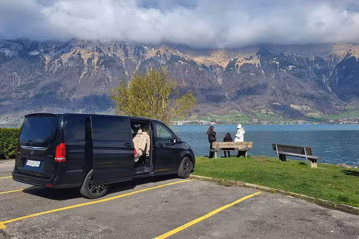 Comfortable van parked by a serene lake with mountains, offering relaxing views on the CLOY private tour.