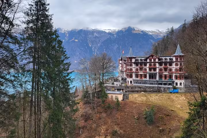 Scenic view of a historic hotel nestled in the Swiss Alps, featured in the CLOY private tour with lake backdrop.
