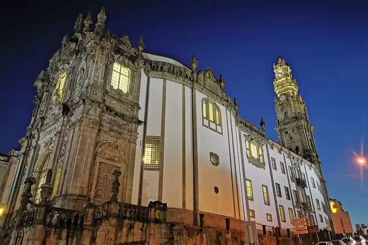 Historic Clérigos Church in Porto illuminated at night, showcasing baroque architecture on a private day trip from Lisbon.