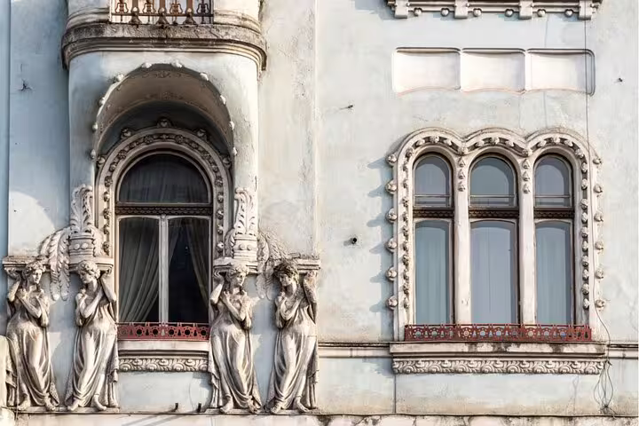 Ornate Art Nouveau building facade with caryatid sculptures and arched windows in Cluj-Napoca