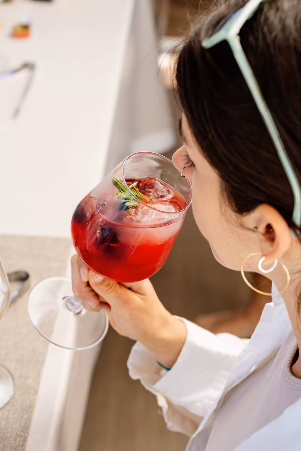 Participant sipping a berry cocktail with ice and rosemary garnish during an interactive cocktail masterclass