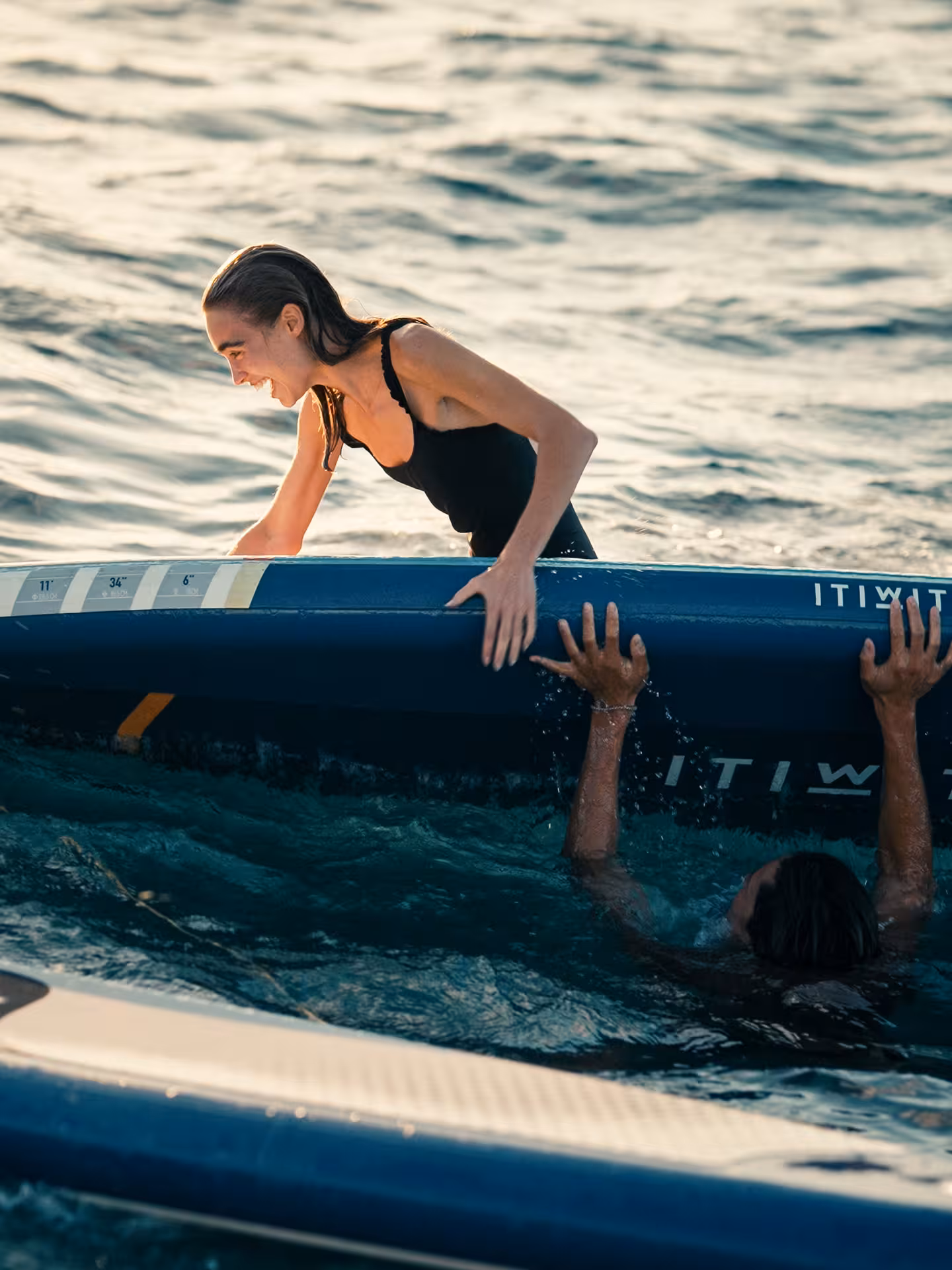 Friends laughing on paddleboard in the sea, a fun pre-cocktail masterclass beach activity in Barcelona