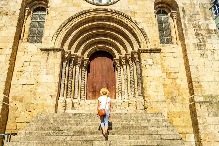 Visitor approaching the historic entrance of Coimbra Cathedral on a sunny day during a private religious tour from Lisbon.