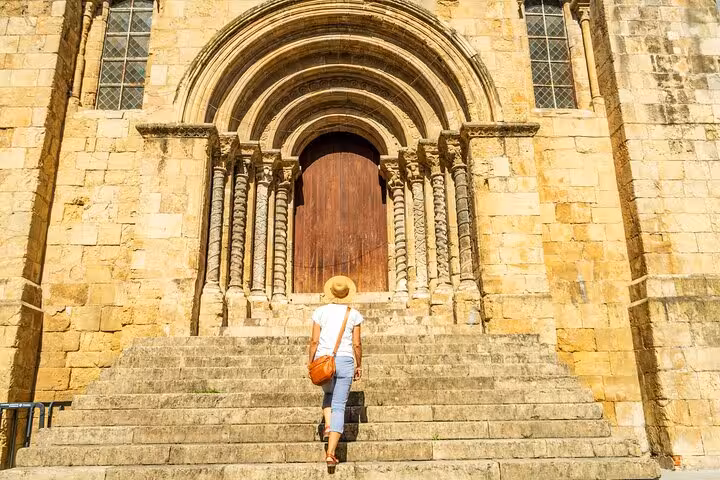Traveler climbing steps to Coimbra's ancient cathedral, showcasing Portugal's rich architectural heritage.