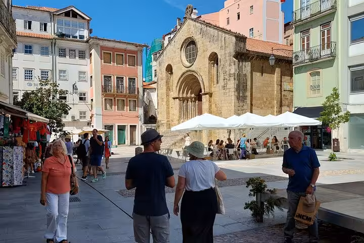 Tourists exploring a historic square in Coimbra with ancient architecture and lively street cafes, perfect for a walking tour.